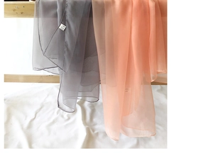 Detail of lightweight gray and coral beach shawls hanging on a wooden rack