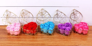 Five heart-shaped wire gift baskets filled with colorful scented soap roses on wood surface