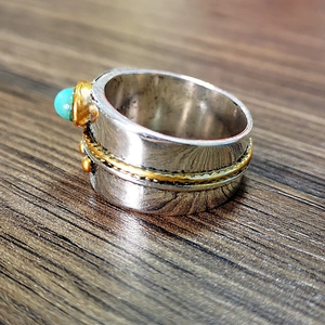 Detailed close-up of wide silver ring featuring a turquoise stone and gold beaded trim