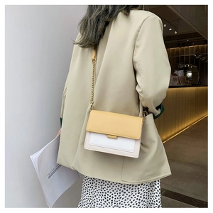 Detail of color-block flap crossbody bag with gold chain strap on a blazer outfit