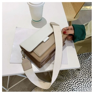 Detail view of khaki and white colorblock crossbody bag with wide strap and gusseted sides