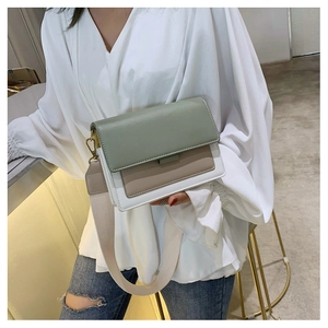 Detail of a color-block crossbody bag with wide strap and gold metal buckle hardware