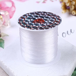 Macro shot of white elastic crystal string roll for jewelry DIY on stone base