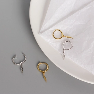 Orecchini a fulmine minimalisti in oro e argento su un piatto bianco pulito