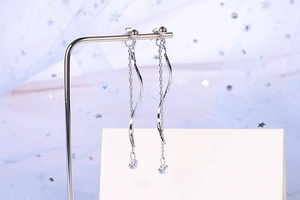 Detail of silver S-shaped wave tassel earrings with sparkling rhinestones and chains