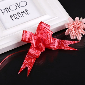 Close-up of red gift bow with gold rose pattern on a black decorative background