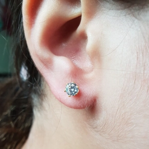 Detail of disposable piercing gun with crown stud worn on ear with clear cubic zirconia