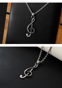 Close-up of a silver treble clef pendant with a twisted rope chain on black leather
