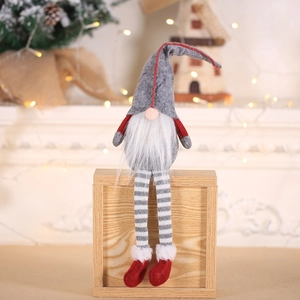 Nordic Christmas gnome plush with long striped legs sitting on a wooden gift box