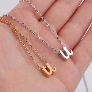 Colliers avec pendentif lettre U en or et argent portés sur la paume de la main