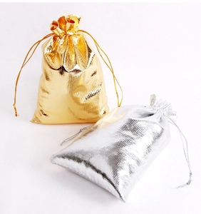 Detailed close-up of textured gold and silver drawstring gift bags on white background