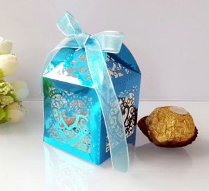 Detail of laser-cut heart pattern on blue metallic wedding candy box with ribbon