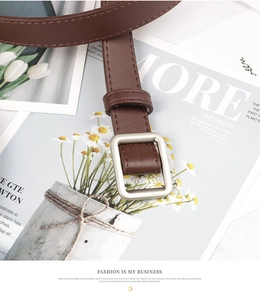 Detailed shot of brown leather belt with square metal buckle on fashion magazine background