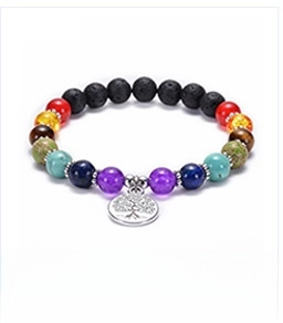 Macro detail of natural lava stones and 7 chakra beads with a silver tree of life charm