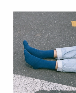 Detail of dark blue ribbed cotton socks for men paired with washed denim jeans