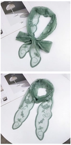 Detail of green mesh lace scarf featuring floral embroidery tied in a delicate bow