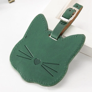 Detalle de etiqueta de equipaje de cuero verde con forma de gato y hebilla metálica