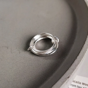 Macro shot of 925 sterling silver multi-layer intertwined rings on a gray display tray