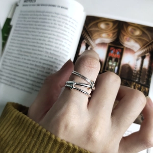 Detail of multi-layer layered silver knotted ring worn with a yellow knit sweater