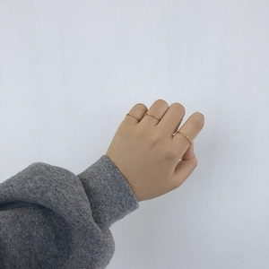 Detail of three minimalist slim gold rings worn on fingers for layered styling