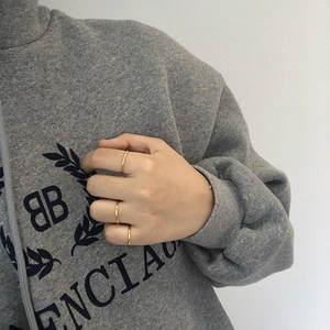 Close-up of three slim minimalist gold rings worn on fingers with a neutral background