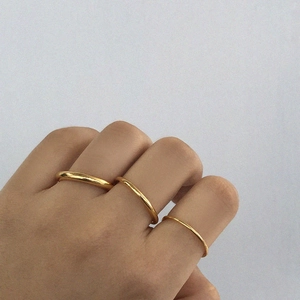 Detailed comparison of three polished gold bands in different thicknesses on a hand