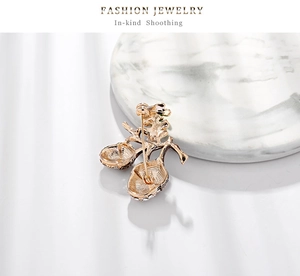 Macro view of crystal-encrusted hazelnut brooch with brushed gold metal texture
