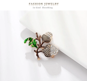 Macro detail of acorn brooch with sparkling rhinestones and green enamel leaves