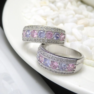 Macro shot of silver bands with three rows of pink and white micro-set zircon stones