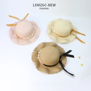 Detail of straw sun hats with elegant pearl chains, wavy brims, and ribbon ties