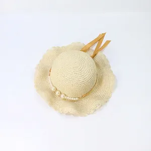 Detailed close-up of straw hat featuring wavy brim, gradient pearls and yellow ribbon