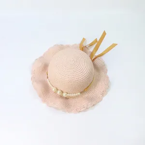 Detailed view of pink straw hat with wavy brim, white pearl beads and yellow ribbon