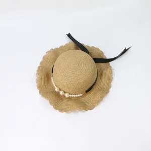 Detail of straw hat with scalloped wavy brim, black ribbon and elegant pearl accents
