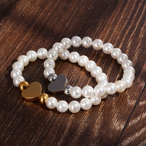 Shell pearl bracelet set with heart pendants in gold and silver on dark wood background