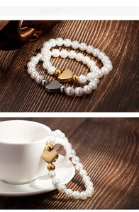 Dual-color pearl heart charm bracelets on wood background and coffee cup display