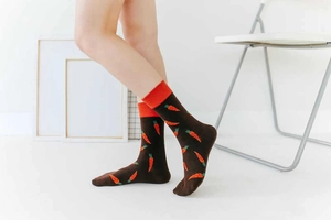 Detail of dark brown cotton crew socks with orange carrot patterns on model legs