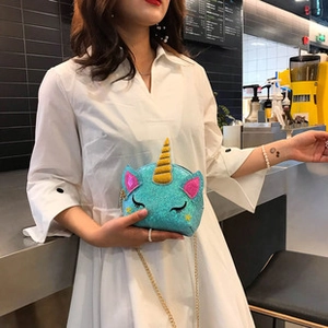 Blue sequin unicorn crossbody bag with golden horn and chain strap on a model