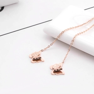 Boucles d'oreilles papillon en or rose avec pampilles sur un fond blanc épuré