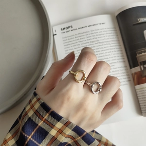 Detail of minimalist gold and silver geometric oval rings worn on hand with magazine