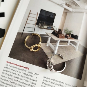 Macro detail of minimalist gold and silver knot rings on a vintage magazine page