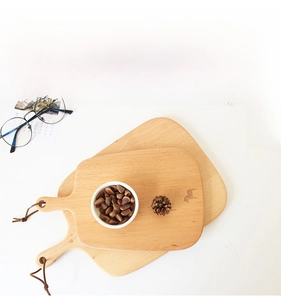 Macro detail of natural beech wood cutting boards with leather hanging straps on a white desk