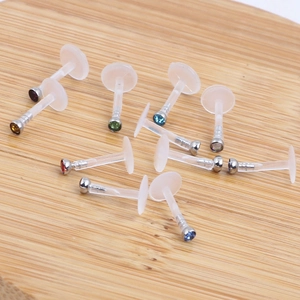 Set of flexible acrylic labret studs with colorful crystal tops on wooden surface