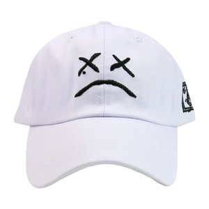 Detailed close-up of the black sad face embroidery on a white cotton baseball cap