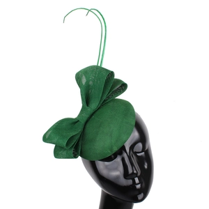 Detail of green fascinator hat with elegant mesh bow and feather-like accents on mannequin