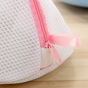Fine mesh polyester bra laundry bag with pink zipper and handle on wooden background
