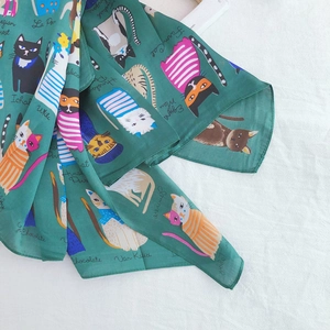 Detail of green silk scarf featuring various cat breeds and elegant floral illustrations