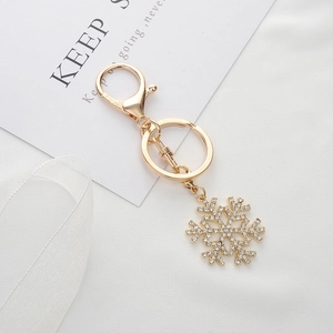 Exquisite golden snowflake keychain with sparkling white rhinestones on white fabric