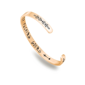 Macro detail of rose gold stainless steel cuff featuring Keep Fucking Going engraving