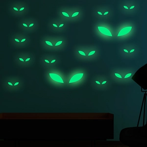 Luminous green Halloween eye stickers glowing brightly on a dark wall background