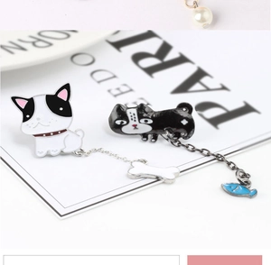 Detail of cartoon dog enamel brooches with bone and fish charms on white background